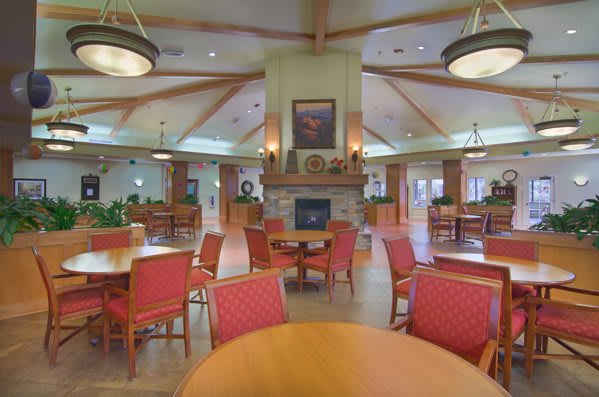 A cozy dining area featuring tables and chairs with a central fireplace.