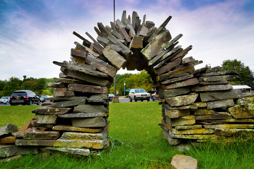 A beautifully crafted stone archway made from layered stones, set against a lush green backdrop.