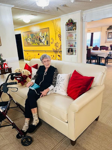 An elderly woman enjoys a cozy moment on the sofa in her beautifully decorated living room.