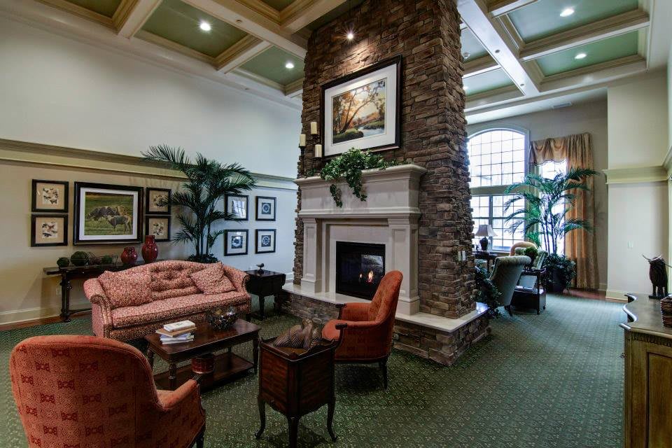 A cozy and elegantly designed living room featuring a stone fireplace, artwork, and comfortable seating.