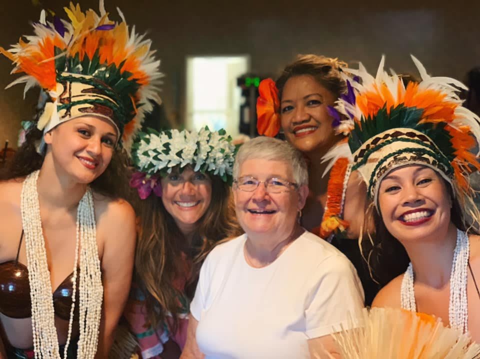 A group of women smiling and wearing colorful traditional headdresses.