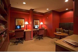 A cozy office space with two computer workstations, red walls, and warm lighting.