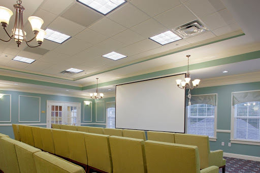 A well-lit meeting room featuring comfortable seating and a large presentation screen.