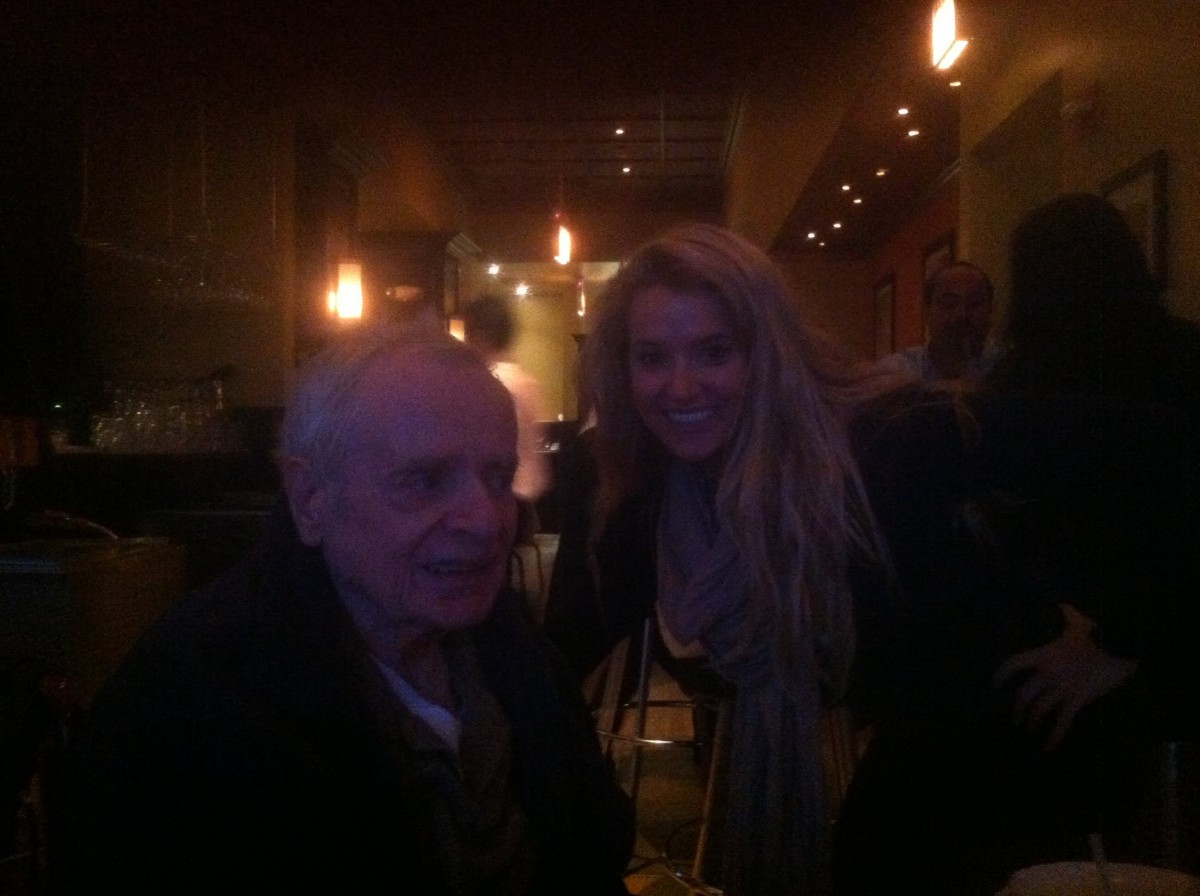 Two people smiling in a dimly lit restaurant.