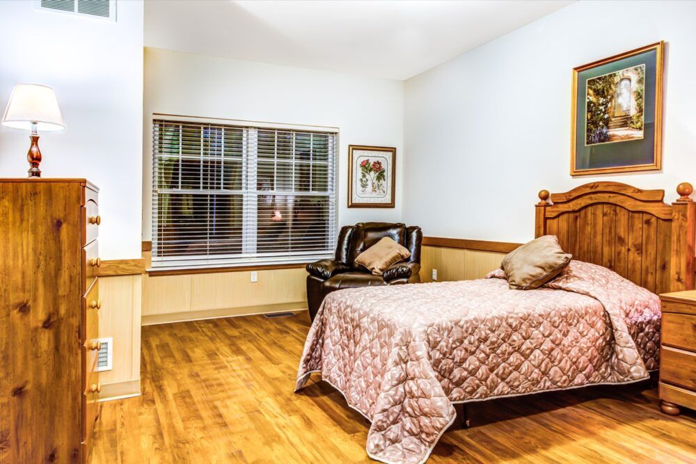 A cozy bedroom with wooden flooring and a comfortable bed near a window.