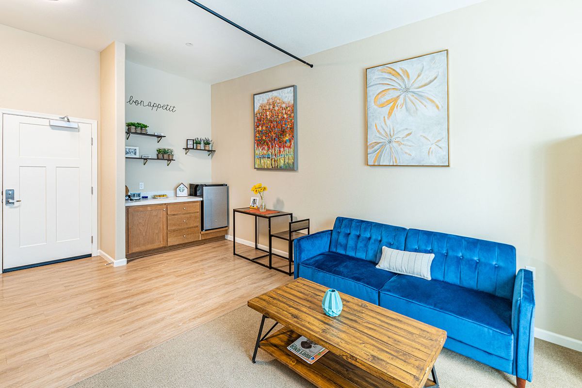 A modern living room featuring a blue sofa, wooden coffee table, and minimalist artwork.