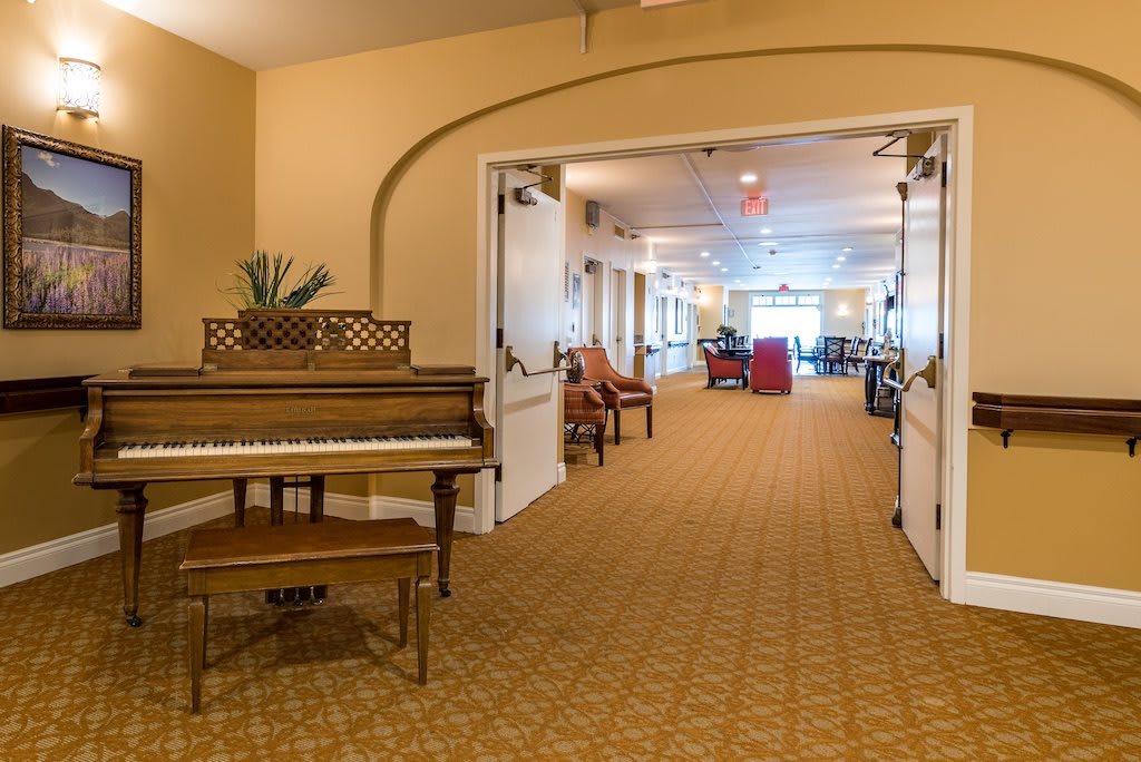 A spacious hallway with a piano and seating area.