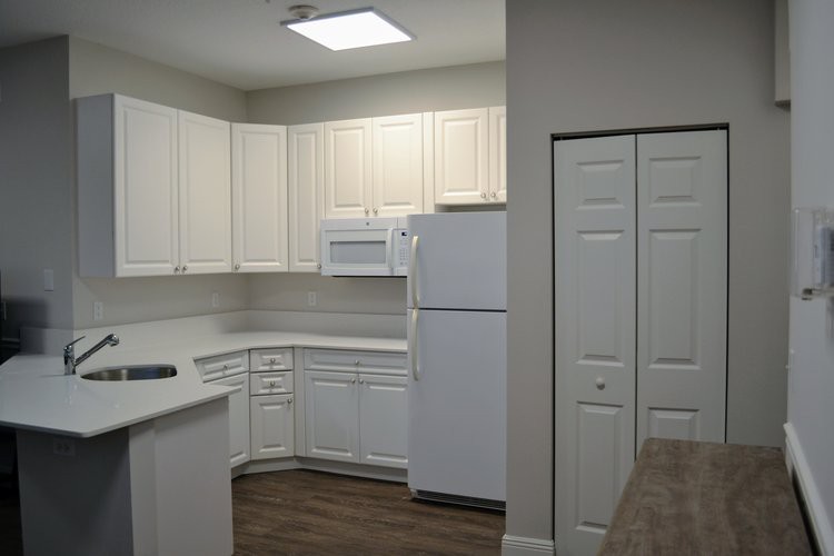 A modern kitchen with white cabinets and appliances.