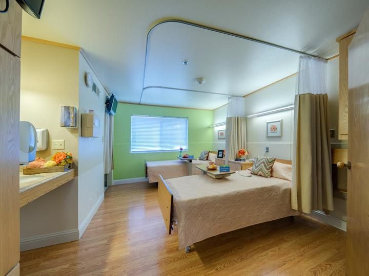 A clean and organized hospital room with two beds separated by a curtain.