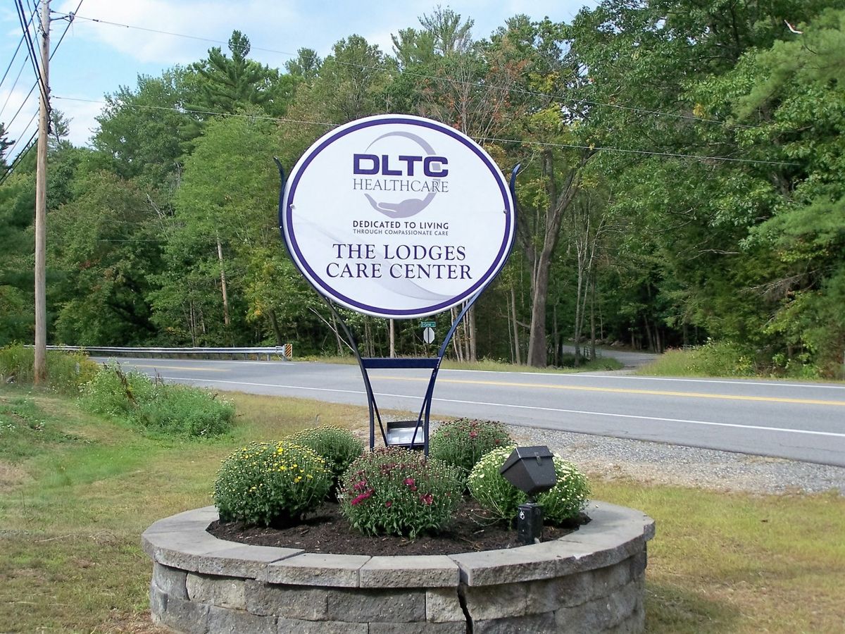 A landscaped roadside sign for DLTC The Landscape Care Company.