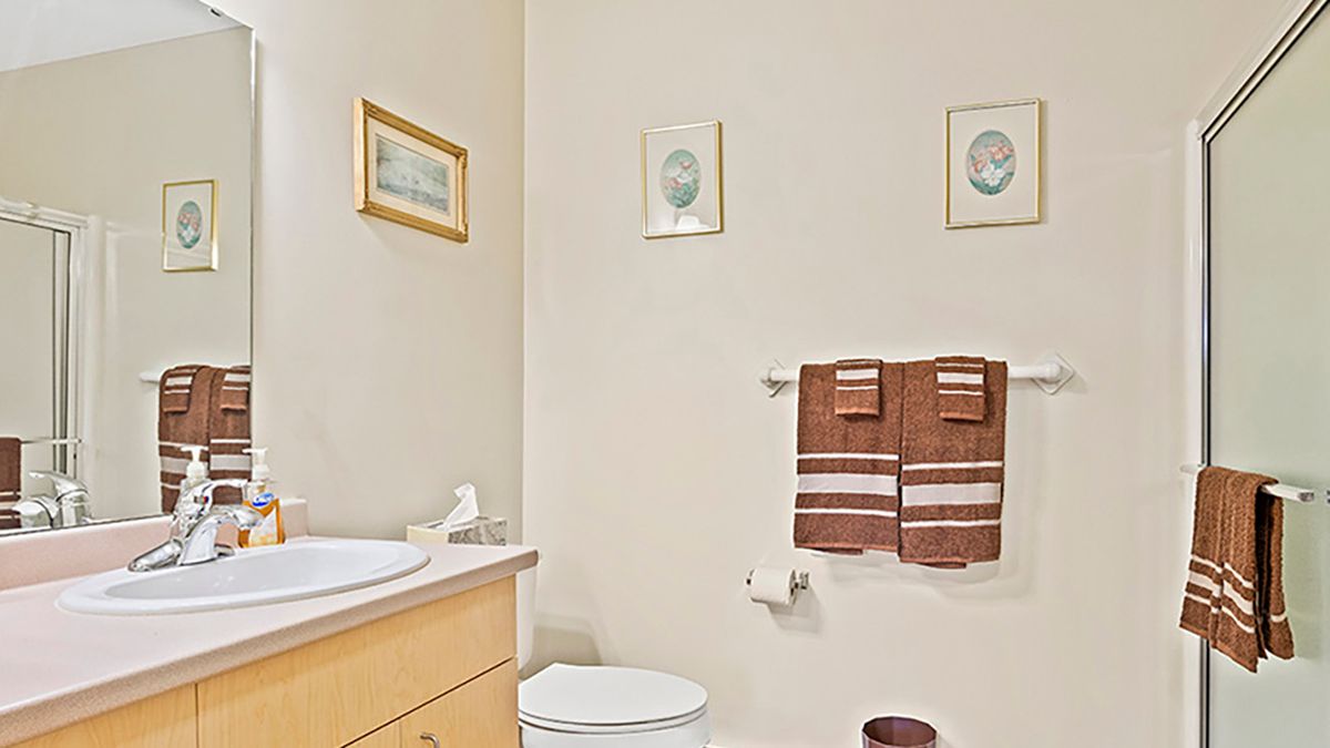A neatly arranged bathroom featuring a toilet, sink, and decorative towels with framed artwork on the walls.