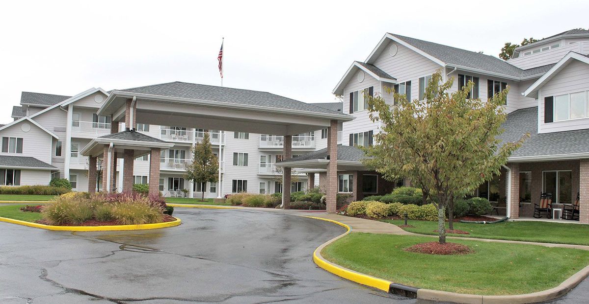 A view of a residential building with a covered entrance and landscaped driveway.