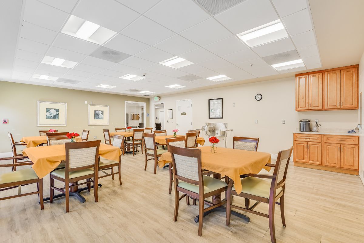 A well-lit dining area with multiple tables and chairs, arranged for a communal setting.