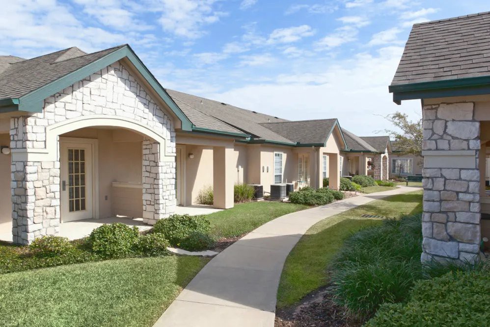 Suburban housing with a paved pathway and neatly landscaped gardens.