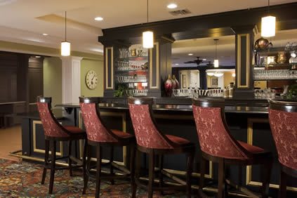 A cozy bar interior with upholstered chairs lined up at the counter.