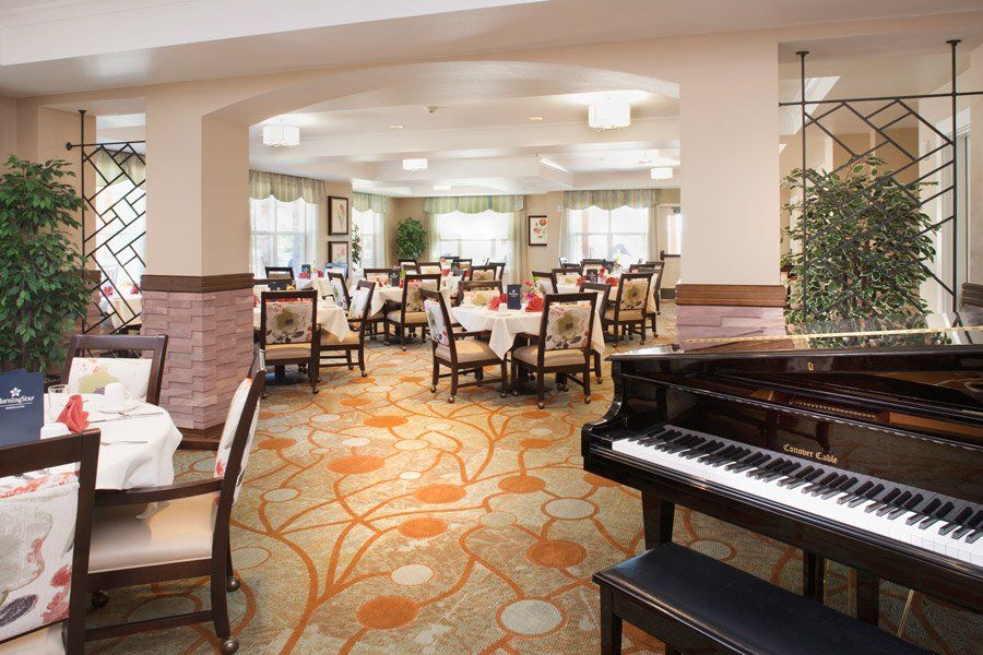 An elegant dining room with a grand piano and beautifully set tables.
