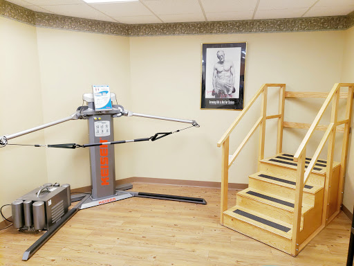 A rehabilitation room featuring exercise equipment and a set of stairs for physical therapy.