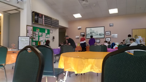 A vibrant community center space with colorful tables, where people are engaged in various activities.