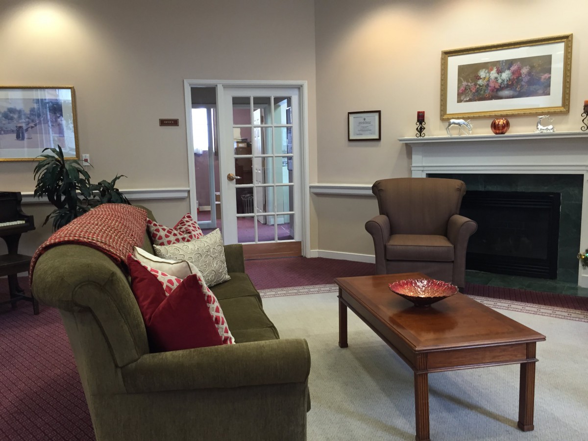 A cozy living room with a couch, armchair, and coffee table in front of a fireplace.