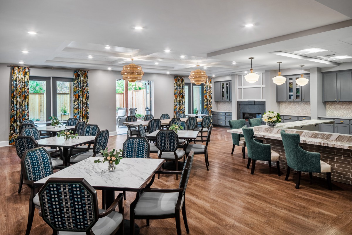 A modern dining room with elegant tables and chairs, featuring stylish lighting fixtures and a wooden floor.