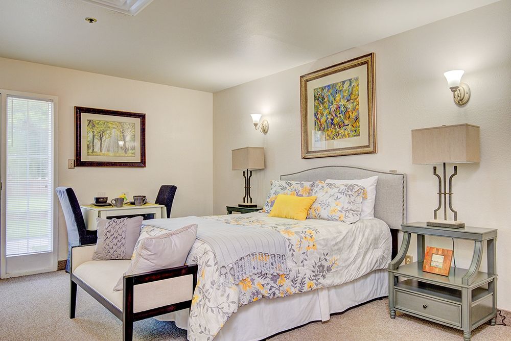A cozy bedroom with elegant decor, featuring a comfortable bed, stylish lamps, and framed artwork on the walls.