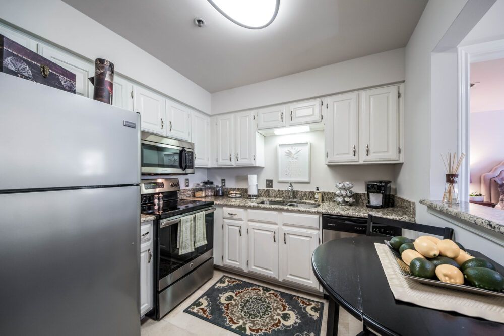 A modern kitchen with white cabinets, a refrigerator, and stainless steel appliances.