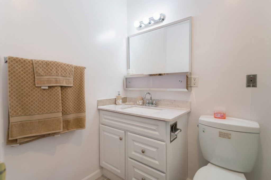 A neatly arranged bathroom with a white vanity, mirror, and towel.