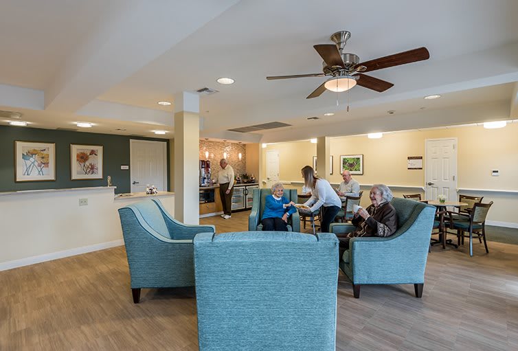 People interacting in a cozy living room setting with comfortable armchairs and soft lighting.