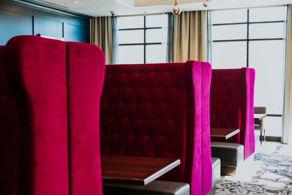 A modern restaurant interior with plush red booth seating.