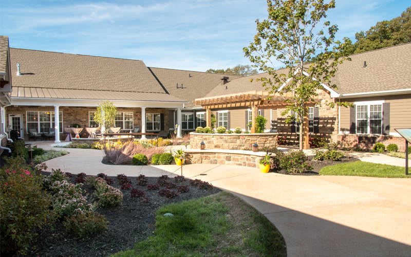 A well-maintained garden and patio area outside a large building with landscaped pathways.