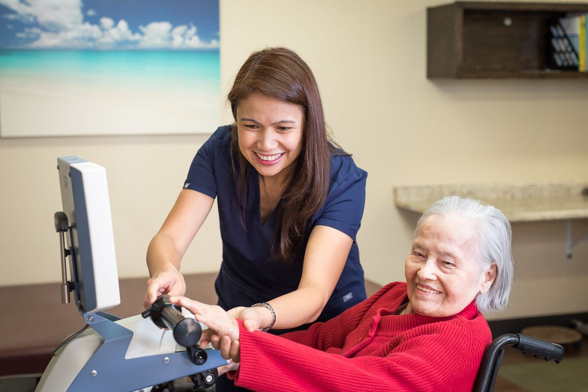 A healthcare worker assisting a smiling elderly woman.