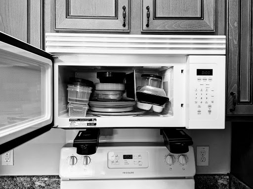 A view of a kitchen microwave filled with plates and cooking items.