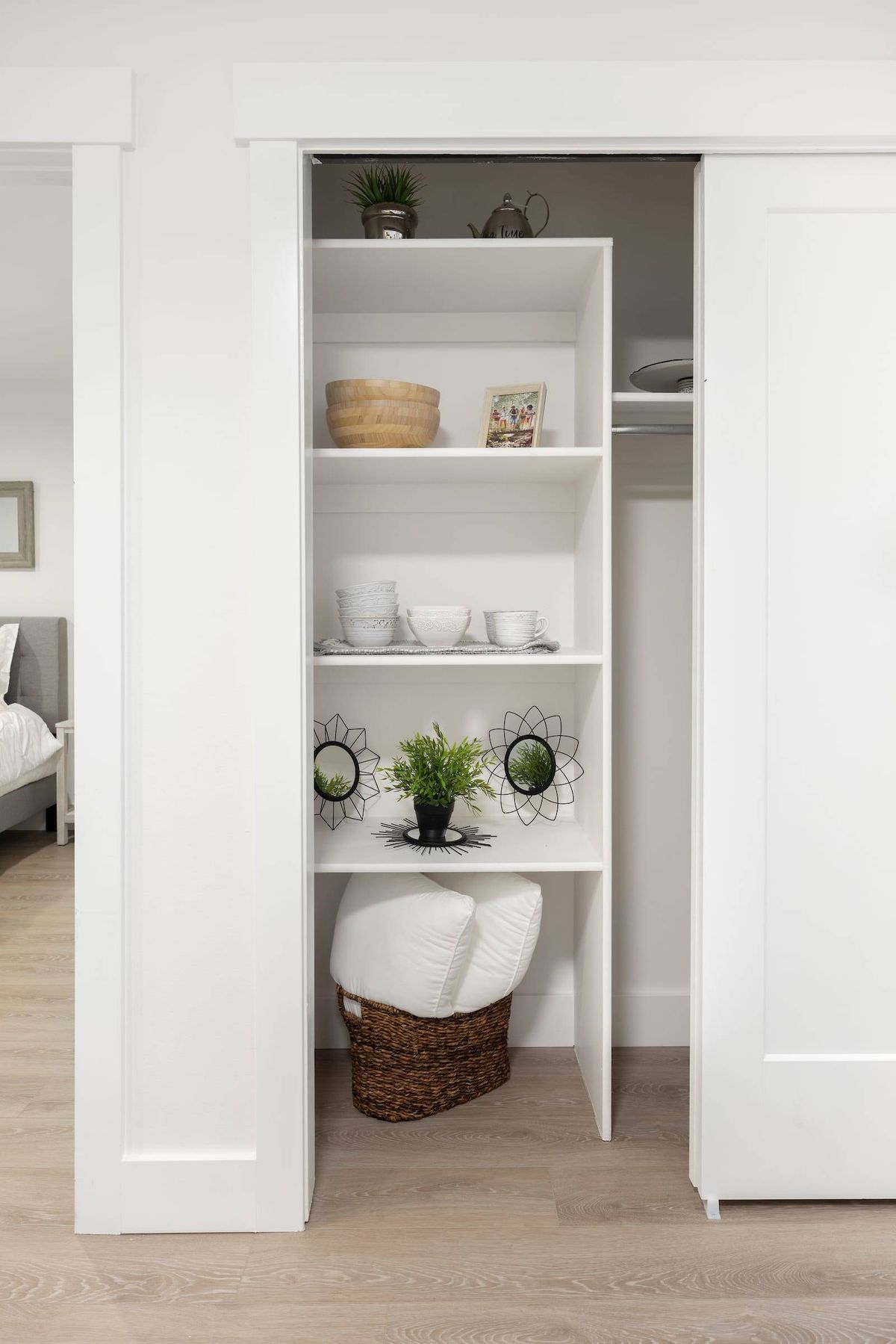 A neatly organized closet with white shelves, decorated with plants and various items.