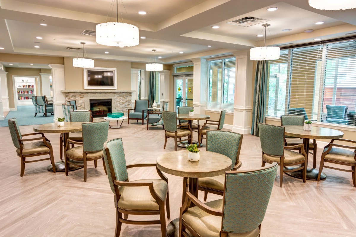A cozy and well-lit dining area with modern decor, featuring several tables and chairs arranged in a spacious layout.