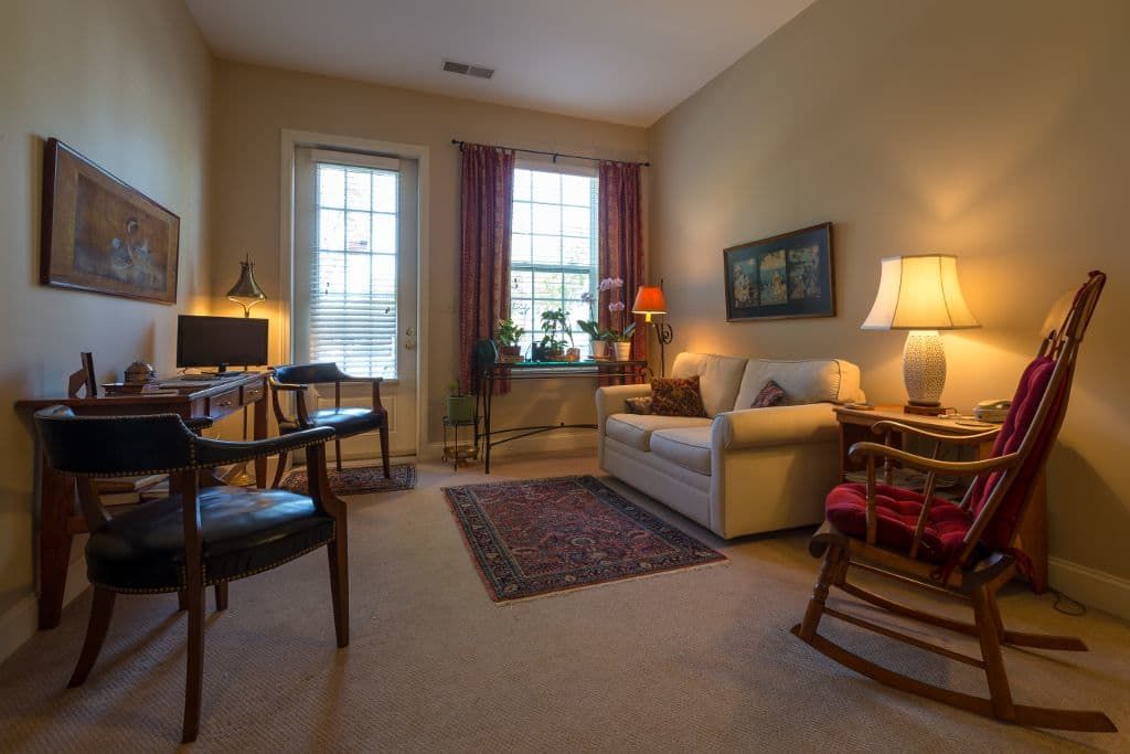 A cozy living room featuring a sofa, lamps, and a decorative rug.