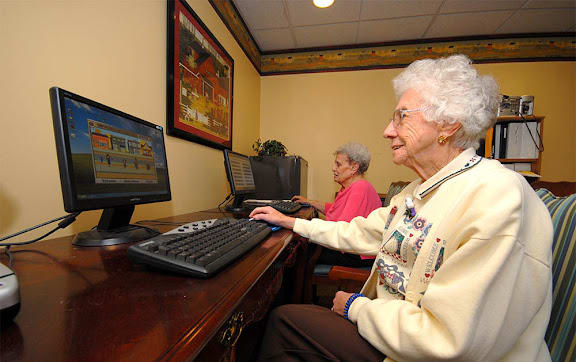 Two elderly people using computers in a learning environment.