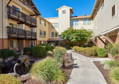 A well-maintained apartment complex courtyard featuring a landscaped garden and pathway.