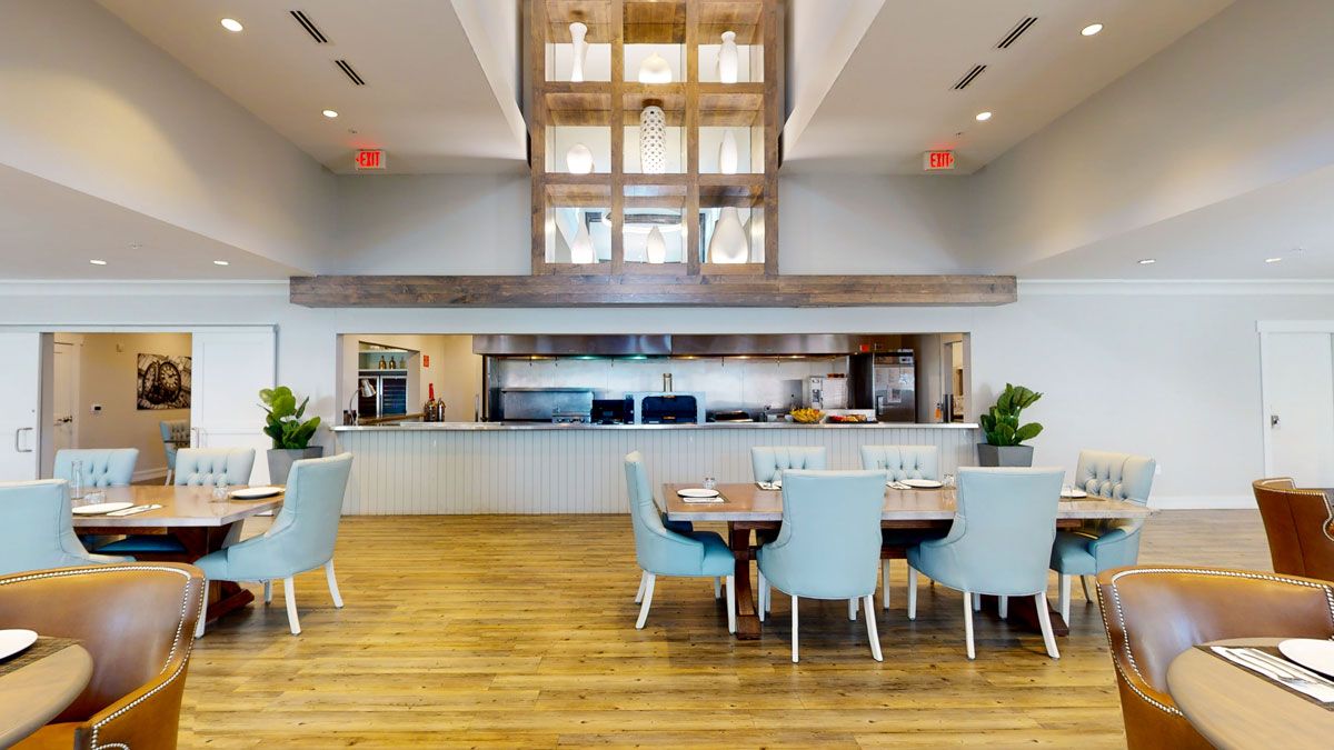 A modern open-concept kitchen and dining area with blue chairs and wood flooring.