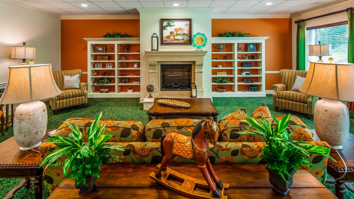 A cozy living room featuring a fireplace, bookshelves, and a decorative rocking horse.