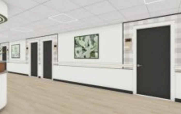 A modern hospital corridor with multiple doors and artwork on the wall.