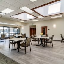 A modern dining area with multiple tables and chairs, well-lit by natural light.