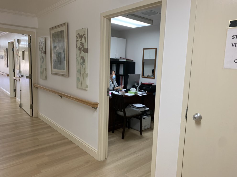A view of an office through a hallway, featuring a desk with a computer and artwork on the walls.