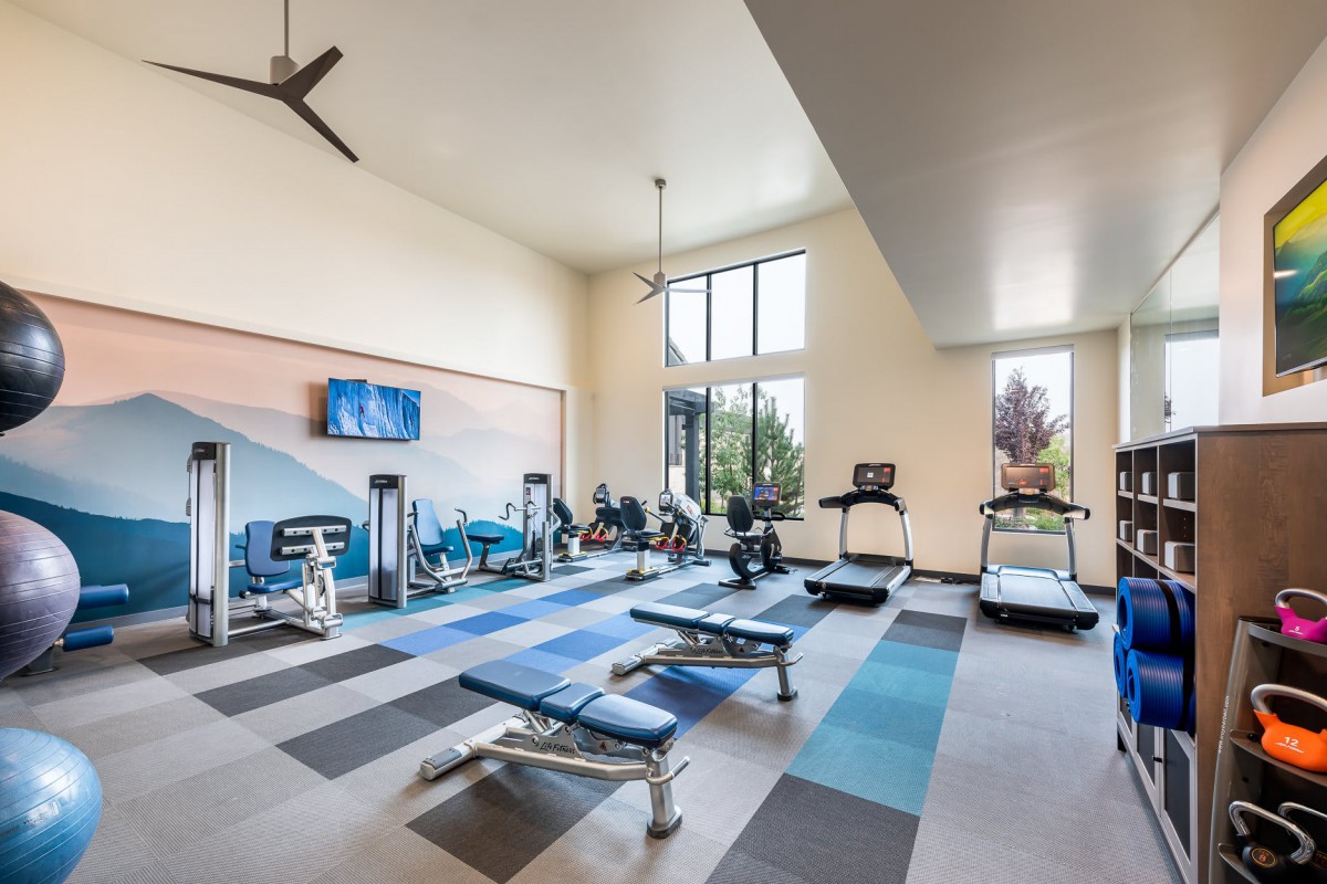 A modern fitness center with various exercise equipment, including treadmills and benches.