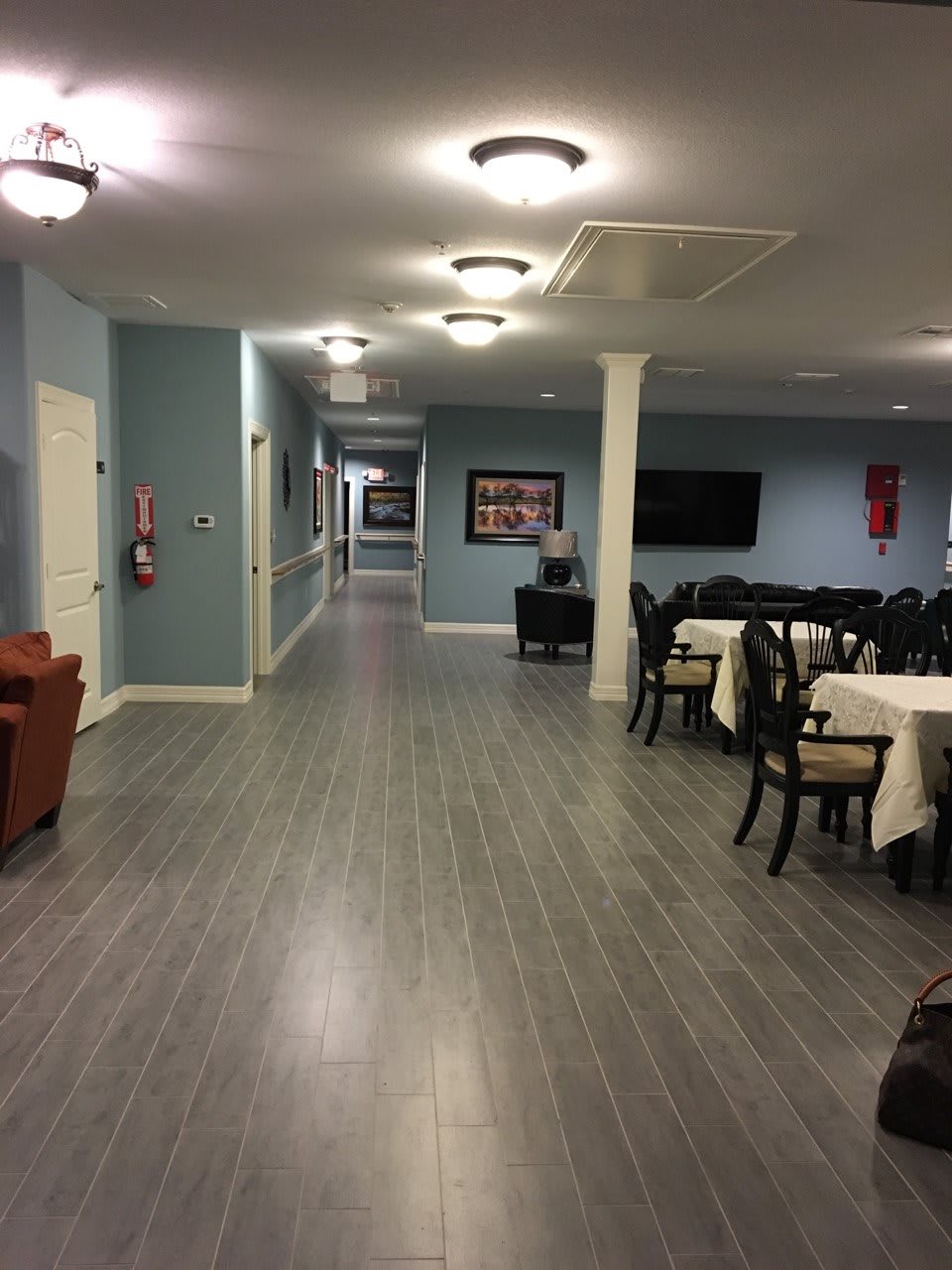 A hallway leading to a dining area with tables and chairs, featuring modern lighting and decor.