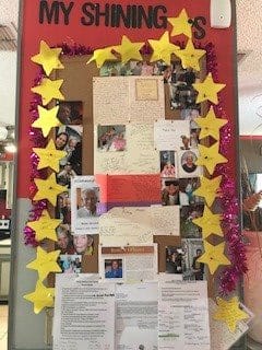 A decorated bulletin board with photos and star-shaped embellishments.