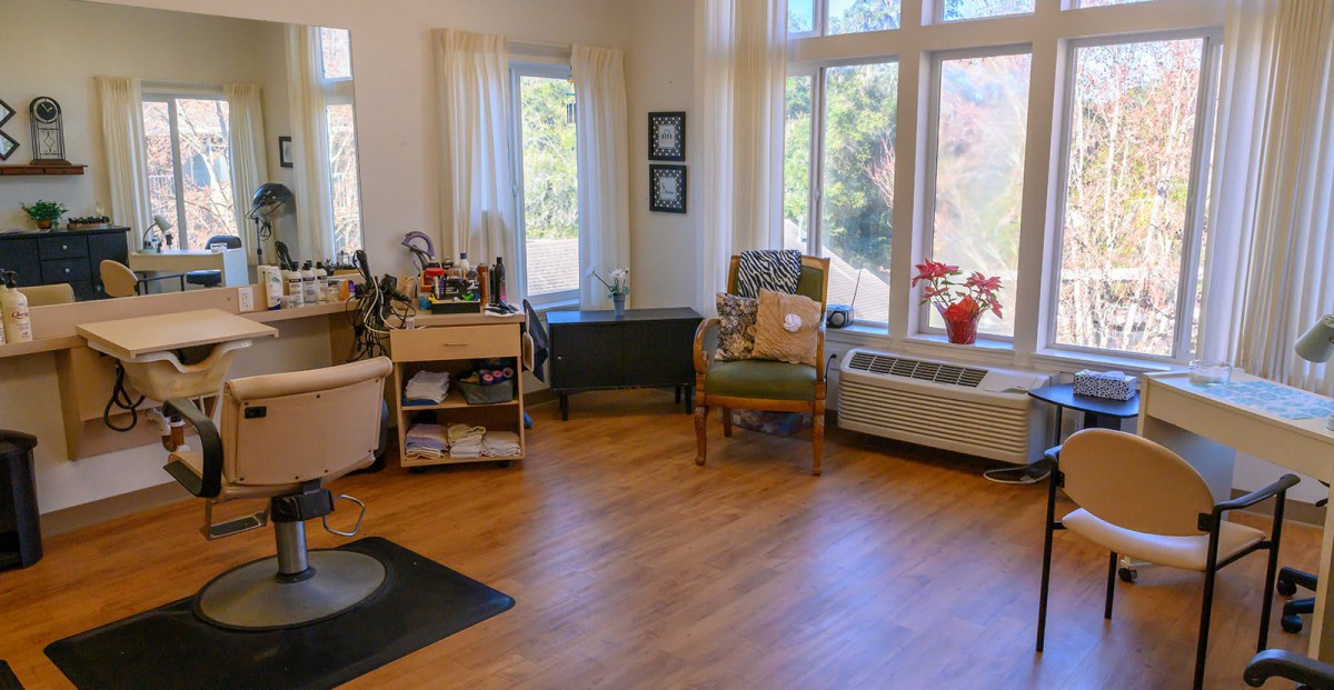 A cozy living room with large windows, wooden floors, and comfortable seating.