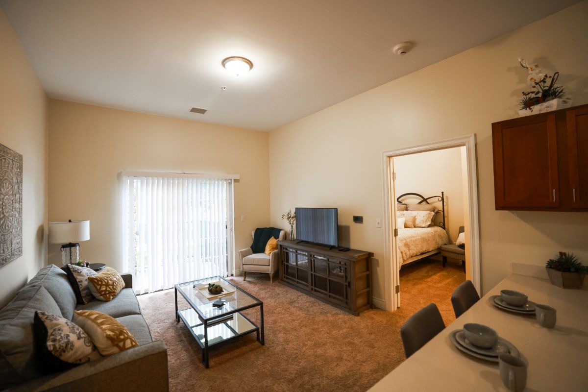 A cozy apartment living room with modern furniture and a view into the bedroom.