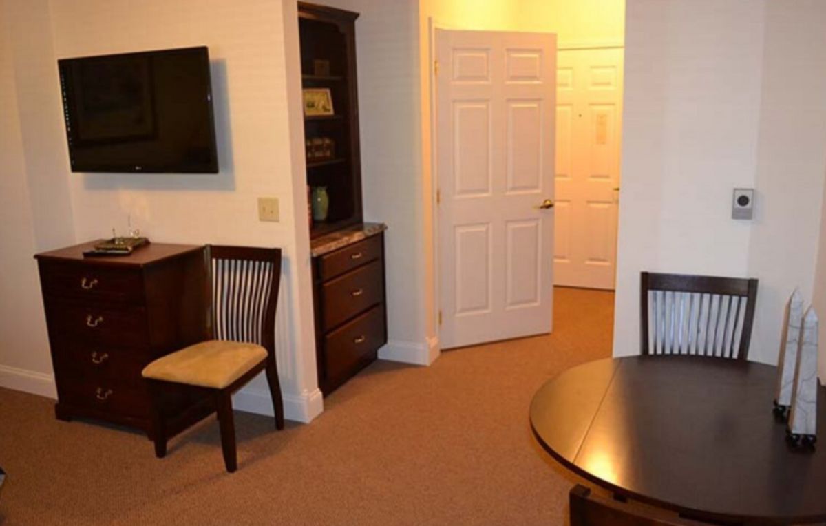 A cozy living room with seating, a TV, and a wooden shelving unit near an open door.