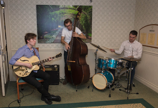 A jazz trio performing live, featuring a guitarist, a double bassist, and a drummer.