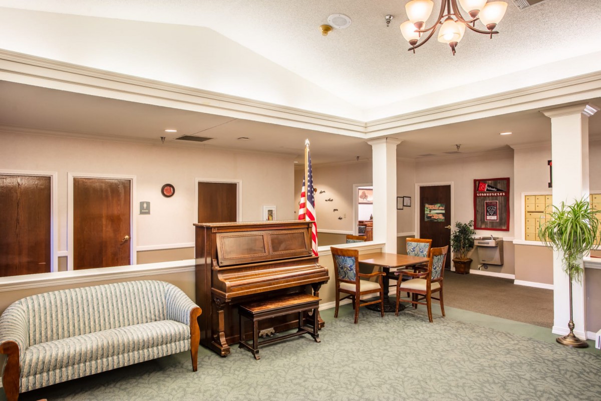 A well-furnished lobby featuring a piano, seating area, and an American flag.